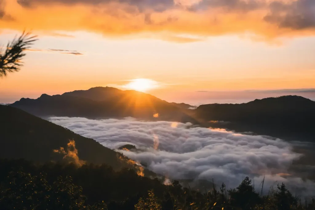 A breathtaking mountain vista at sunrise, featuring a thick blanket of white clouds settled into the valley.